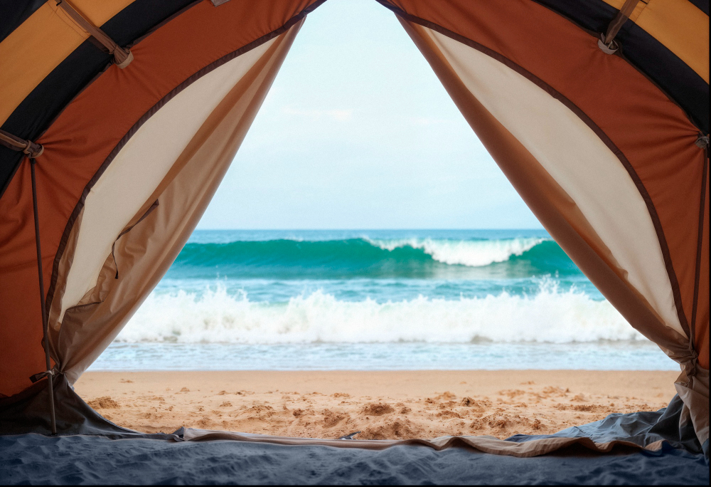 Inside a tent on Block Island, open flaps frame a sandy beach, turquoise waves, and clear sky for a perfect island view.